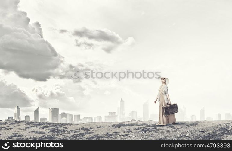 Woman with old suitcase. Beautiful woman with retro suitcase walking on hill top