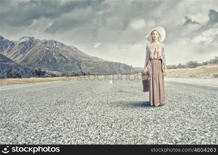 Woman with old suitcase. Beautiful woman with retro suitcase walking on road