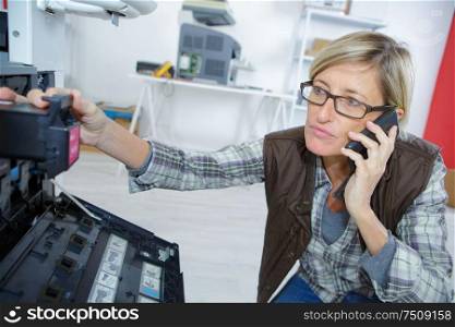 woman with on the phone fixing printer