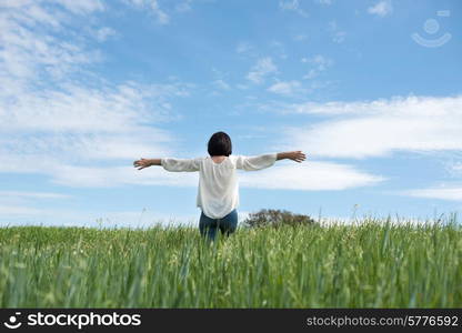 Woman with open arms in green field