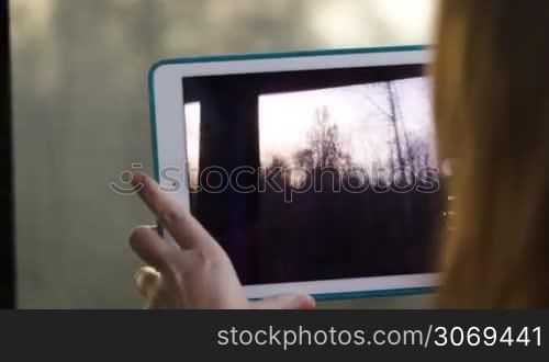 Woman with pad in the train making a video of passing landscape