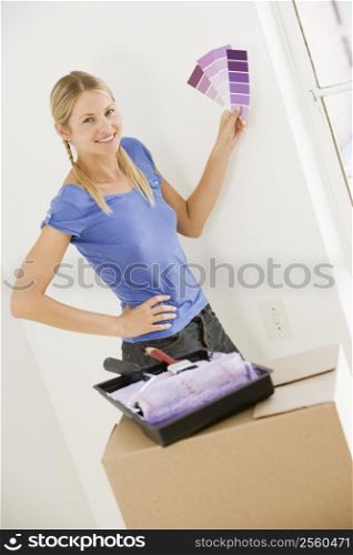 Woman with paint swatches in new home smiling