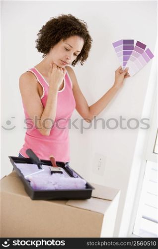 Woman with paint swatches in new home thinking