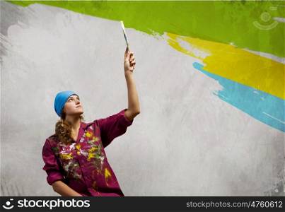 Woman with paintbrush. Young woman painting wall in colors with brush