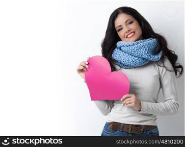 Woman with paper heart. Smiling young woman in warm clothes with Valentine day pink paper heart card in her hands