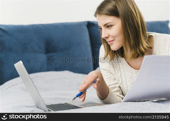 woman with papers browsing laptop