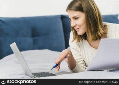 woman with papers browsing laptop