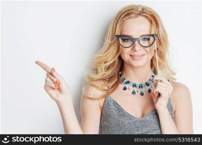 Woman with party glasses. Beautiful funny woman with party paper glasses on stick showing empty copy space, white background