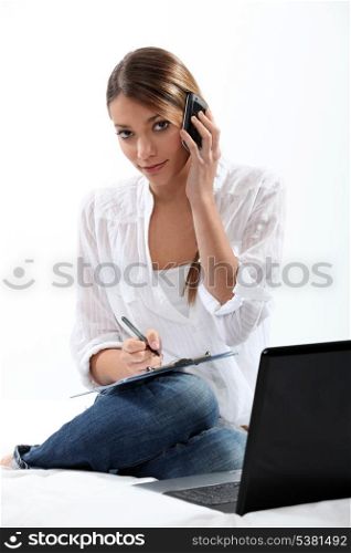 Woman with phone, laptop and clipboard
