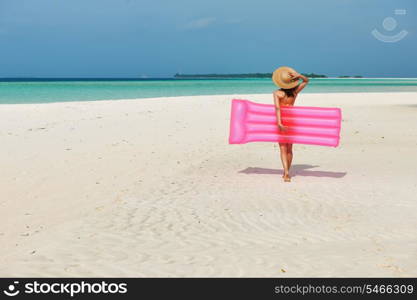 Woman with pink inflatable raft walking at the beach