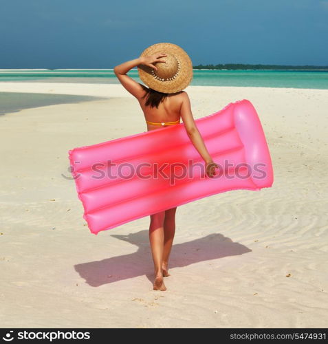 Woman with pink inflatable raft walking at the beach