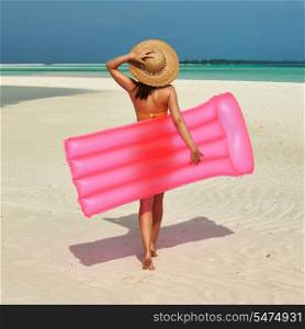 Woman with pink inflatable raft walking at the beach