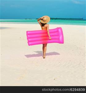 Woman with pink inflatable raft walking at the beach