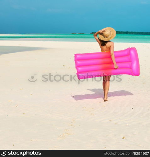 Woman with pink inflatable raft walking at the beach