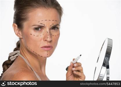 Woman with plastic surgery marks on face holding mirror and marker