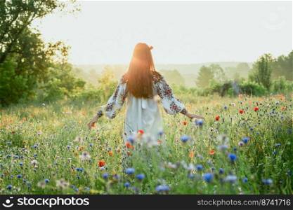 Woman with poppy in hair scenic photography. Blossoming field. Picture of lady with beautiful wildflowers on foreground. High quality wallpaper. Photo concept for ads, travel blog, magazine, article. Woman with poppy in hair scenic photography
