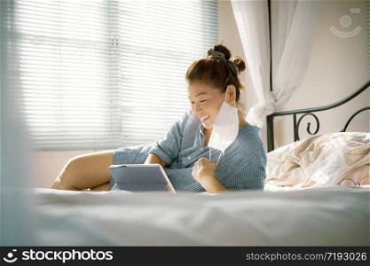 woman with protection mask in hand lying on sofa bed in home living room chatting to internet device