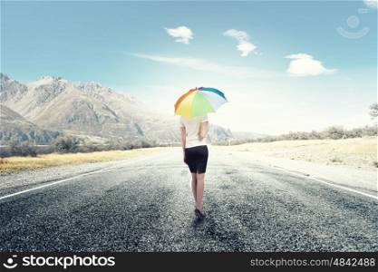 Woman with rainbow umbrella. Young pretty businesswoman with rainbow colorful umbrella walking on road
