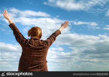 Woman with raised hands against blue sky