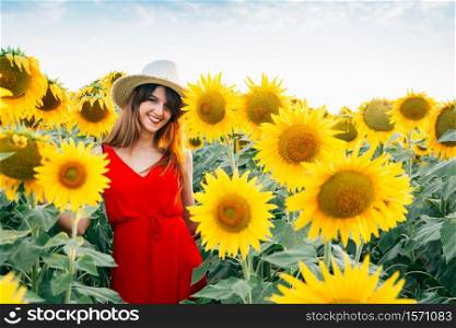 woman with red dress and hat in sunflowers field.. woman with red dress and hat in sunflowers field