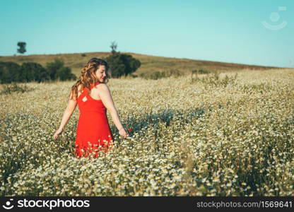 woman with red dress and poppy in hand in the field.