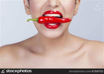 Woman with red pepper between her teeth
