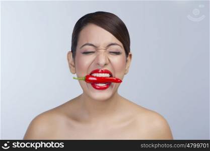 Woman with red pepper between her teeth