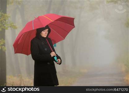 Woman with red umbrella and foggy forest