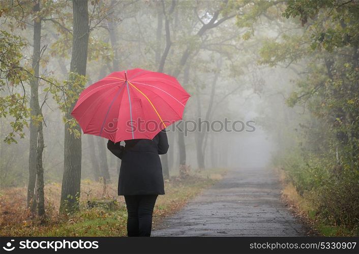 Woman with red umbrella and foggy forest feeling depressed