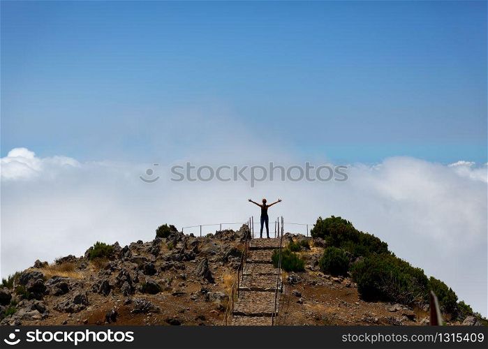 Woman with rising hands standing on the mountain peak at sunset. Woman on the mountain peak