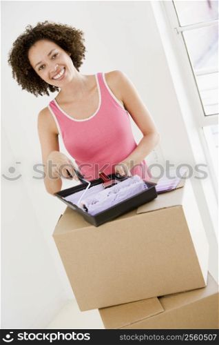 Woman with roller and paint in new home smiling