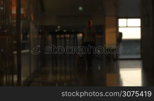 Woman with rolling bag walking at the airport terminal. Going for travel