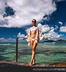 Woman with sarong on a tropical beach jetty at at Seychelles, La Digue.