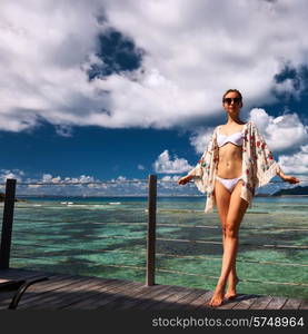 Woman with sarong on a tropical beach jetty at at Seychelles, La Digue.