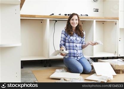 Woman With Self Assembly Furniture In Kitchen