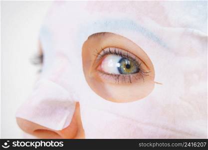 Woman with sheet mask on her face. Girl taking care of skin. Beauty treatment. Skincare.. Woman applying sheet mask on face
