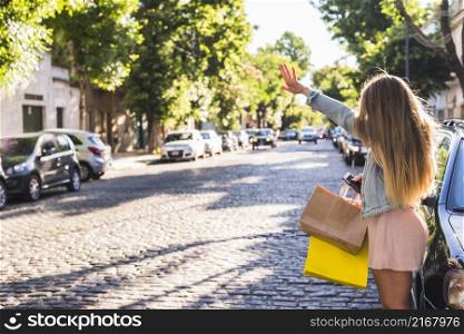 woman with shopping bags catching taxi