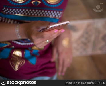 Woman with smartphone at home. Hands of young girl with flash tattoo using mobile device.