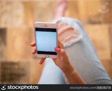 Woman with smartphone at home, white screen. Hands of young girl with flash tattoo using mobile device. High quality photo. Woman with smartphone at home, white screen. Hands of young girl with flash tattoo using mobile device.