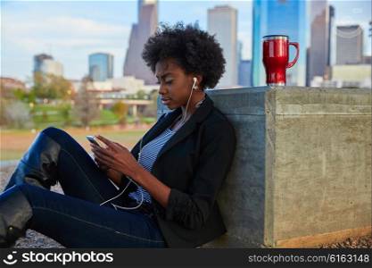 Woman with smartphone sitting in the park listening music dress in black