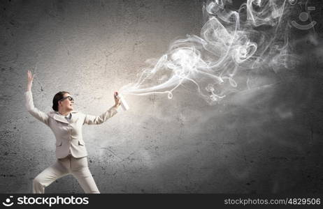 Woman with spray can. Young woman in suit and glasses using aerosol