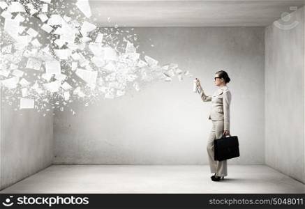 Woman with spray can. Young woman in suit with suitcase spraying paper sheets