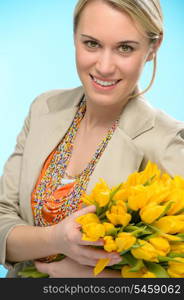 Woman with spring flowers yellow tulips bouquet on blue background