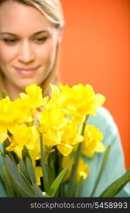 Woman with spring yellow flower narcissus on orange background