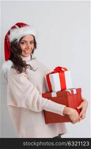 Woman with stack of gifts. Happy woman in Santa hat with stack of Christmas gifts