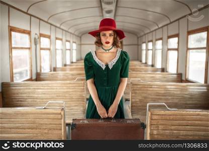 Woman with suitcase in retro train, old wagon interior. Railroad voyage. Vintage journey