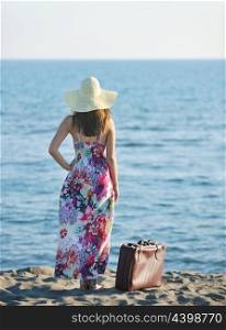 woman with suitcase travel bag on the beach representing exotic and luxury escape and freedom
