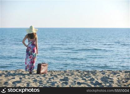 woman with suitcase travel bag on the beach representing exotic and luxury escape and freedom