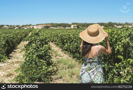 Woman with summer hat watching vineyards in a row