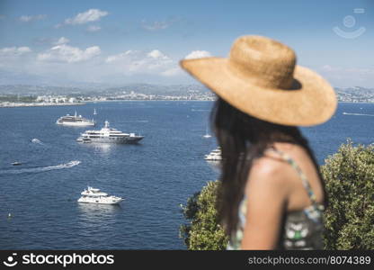 Woman with summer hat watching yachts. French riviera